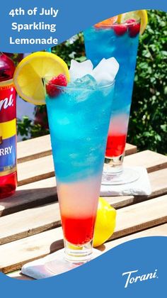 two blue and red drinks sitting on top of a wooden table next to each other