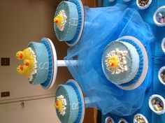 a table topped with cakes and cupcakes covered in frosted rubber ducky decorations