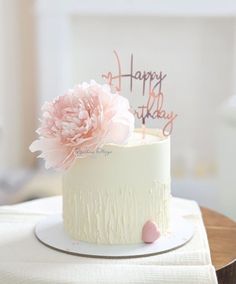 a white cake with pink flowers on top and happy birthday written on the frosting