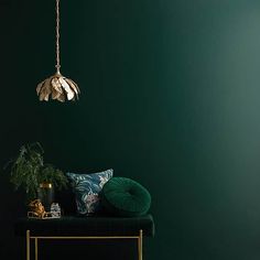 a room with green walls and a gold table lamp hanging from the ceiling above it