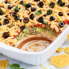 a casserole dish filled with cheese, black olives and guacamole