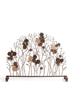 a metal sculpture with flowers and branches on it's sides, against a white background