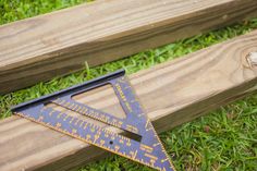 a wooden ruler sitting on top of a green grass covered field next to a piece of wood