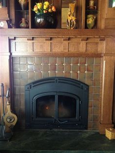 a fire place in a living room next to a book shelf with vases on it