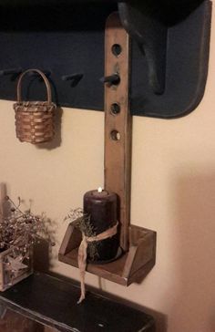 a wooden shelf with a candle and some flowers on it next to a wall mounted clock