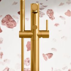 a gold colored faucet is shown with pink flowers on the wall behind it