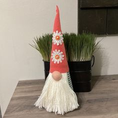 a red and white gnome hat sitting on top of a wooden table next to a potted plant