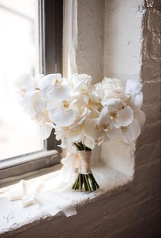 a bouquet of white flowers sitting on top of a window sill