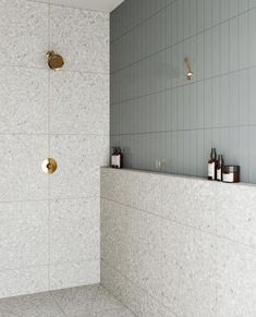 a white tiled bathroom with gold faucet and soap dispensers on the wall