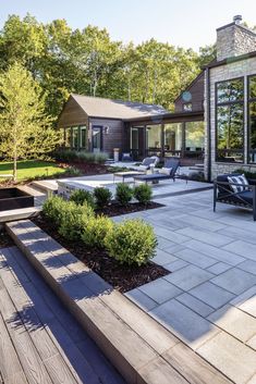 an outdoor living area with seating and landscaping in the foreground, surrounded by trees