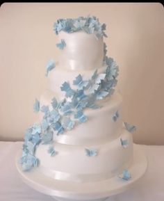 a three tiered cake with blue butterflies on it