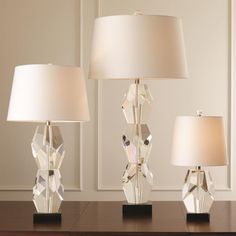 two crystal lamps sitting on top of a wooden table next to a white lamp shade