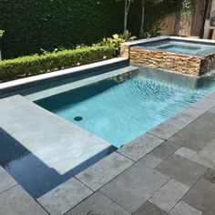 an empty swimming pool in the middle of a backyard with stone walls and landscaping around it