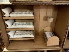 an open cardboard dollhouse with mattresses and pillows