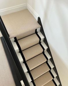 a stair case with beige carpeting and white trim on the bottom half of it