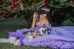 a woman in a purple dress is petting a husky dog wearing a tiara