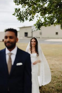 a bride and groom standing under a tree