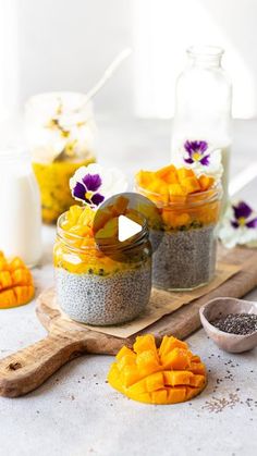 three jars filled with food sitting on top of a wooden cutting board next to flowers