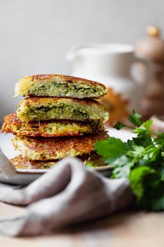 a stack of food sitting on top of a white plate next to a green leafy plant