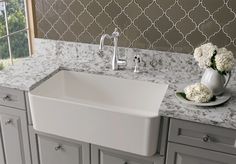 a white sink sitting on top of a counter next to a vase filled with flowers