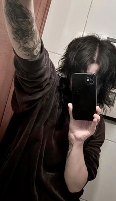 a woman taking a selfie in the mirror with her cell phone and tattoos on her arm