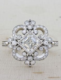 an antique style diamond ring sitting on top of a wooden table