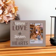 a wooden frame with a dog's face and paw prints on it, next to a candle holder