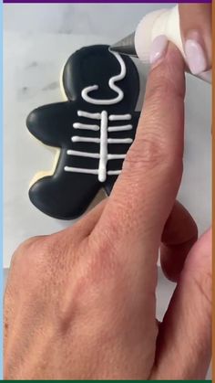 a person is cutting out a cookie with white icing on it, and then using a sharpie to decorate the cookies