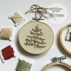 the embroidery pattern is being worked on with thread and needles, including two spools