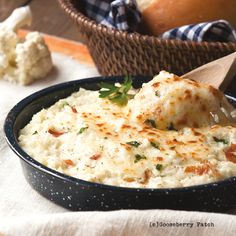 a bowl filled with mashed potatoes on top of a table next to some bread