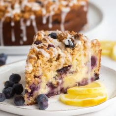 a slice of blueberry crumb cake on a white plate with lemon wedges