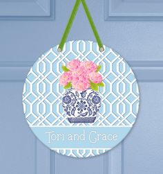 a personalized ornament hanging on a door with pink flowers in a vase