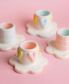 three miniature cups and saucers on a pink surface