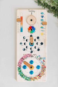 a wooden board with an image of a clock on it and plants next to it