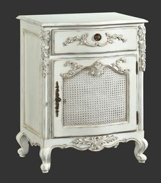 an antique white cabinet with ornate carvings on the doors and drawers, is shown against a black background