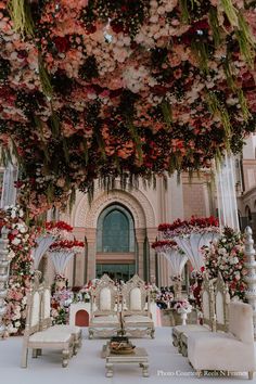 an elaborately decorated wedding ceremony with flowers hanging from the ceiling and candles on tables