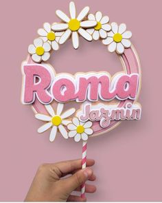 a hand holding a lollipop with the word roma written on it and daisies