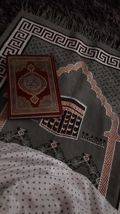 two rugs laying on top of a bed covered in white and black sheets with an intricate design