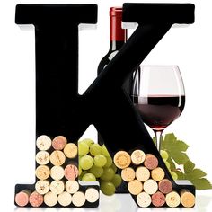 the letter k is made out of wine corks and sits next to a glass of wine