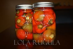 two jars filled with pickled vegetables on top of a table