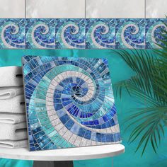 a blue and white mosaic tile design on a wall next to a stack of towels