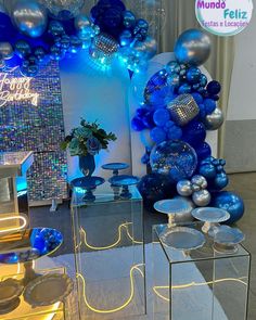 blue and silver balloons are on display in front of a mirror table with mirrored cubes