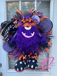 a purple and orange monster wreath with polka dots on the front door for halloween time