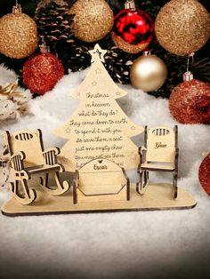 a wooden christmas tree sitting on top of a snow covered ground next to some ornaments