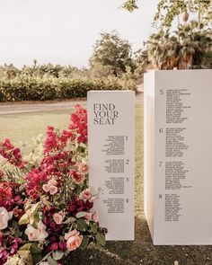 two white signs with flowers on them sitting next to each other in front of a field