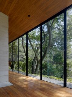 an empty room with wood floors and large windows on the wall, looking out onto trees