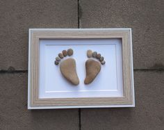 two rocks are placed in a shadow frame to look like baby's foot prints