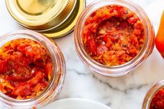 three jars filled with food sitting on top of a white marble counter next to two oranges