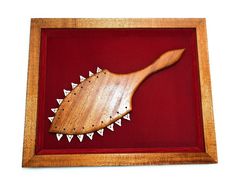 a wooden object with spikes on it is in a frame and has red lining around the edges