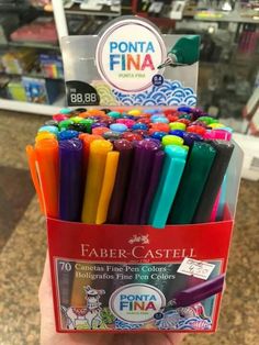 a person holding up a box of colored pens